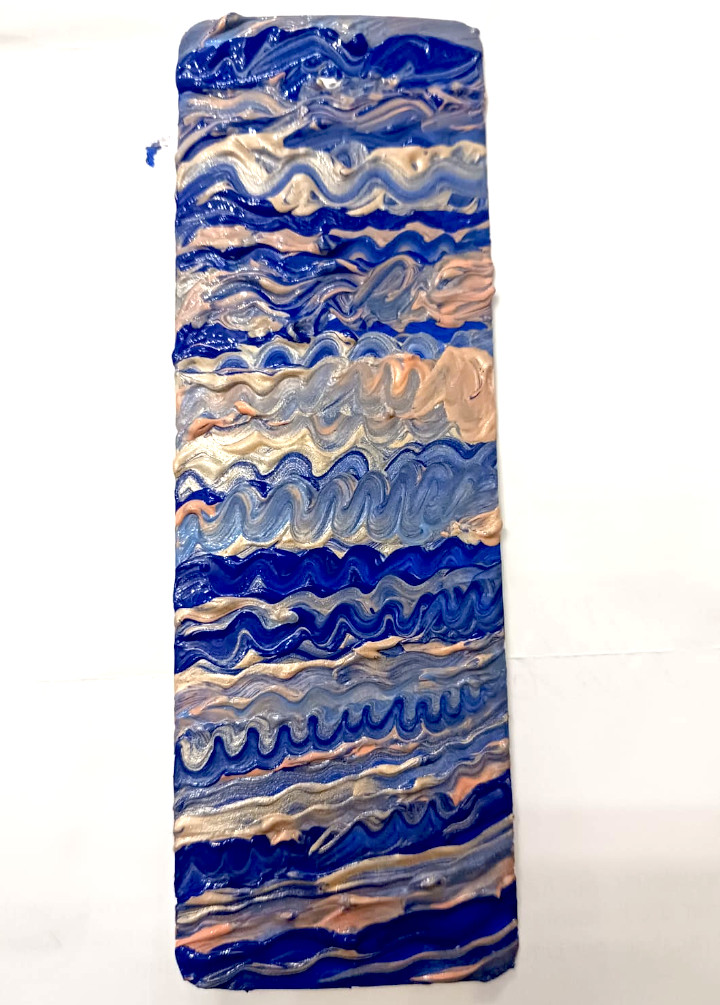 Das gezeigte Lesezeichen ist ein längliches, an den Ecken abgerundetes Kunstwerk, das durchgehend mit wellenförmigen Mustern und einer fühlbaren, plastischen Textur gestaltet ist. Der stark pastöse Farbauftrag erzeugt reliefartige Klangwellen. Hier dominieren hier deutlich dunklere und intensivere Blautöne, während die Grünanteile komplett in den Hintergrund treten.Die Farben verteilen sich in welligen, horizontalen Bahnen von oben nach unten wie folgt:Obere Sektion: Ein sehr dunkles Indigo- und Nachtblau bildet den oberen Rand, gefolgt von einer Schicht aus hellem Champagner- und Beigegold.Obere Mitte: Kräftiges Kobaltblau im Wechsel mit feinen Wellenlinien in zartem Pfirsich- und Roséton.Mitte: Ein hellerer, fast silberner Graublau-Abschnitt, der von einer breiten Welle aus pastösem Rosé/Beige durchbrochen wird.Untere Mitte: Ein dominantes, tiefblaues Band mit stark ausgeprägten Reliefstrukturen, gefolgt von feinen Wellen in Graublau und Champagner.Untere Sektion: Eine schmale Schicht aus glänzendem Silber und Beigegold, die direkt in ein tiefes, dunkles Blau übergeht.Basis: Ein breiter, abschließender Block aus sattem Ultramarinblau am untersten Rand, der durch eine letzte, feine Welle in Pfirsich/Rosa aufgelockert wird.